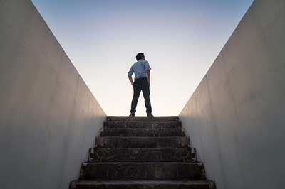 Ein Mann steht auf einer Treppe zwischen zwei hohen Gebäuden