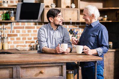 Vater uns Shon trinken am Tisch Kaffee und unterhalten sich